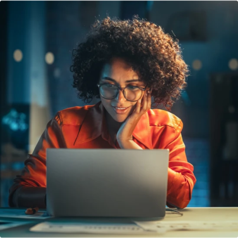 imagem de uma mulher com casaco laranja utilizando o computador portátils